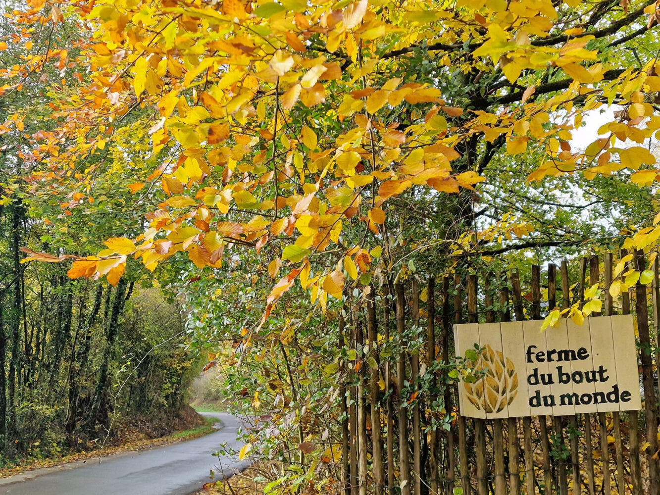 The ferme du bout du monde sign among autumn leaves